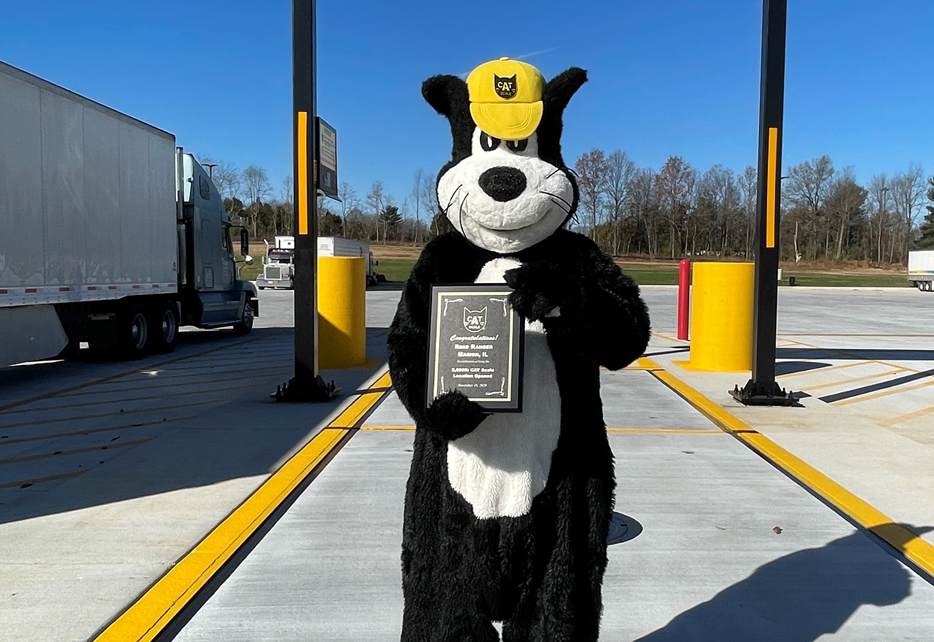 Wade Wright (CAT Scale mascot) on scale with 2000th CAT Scale award plaque later presented to Marko Zaro, CEO Road Ranger.
